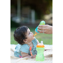 Infant being fed with teal silicone squeeze feeder spout and puree