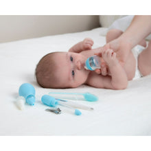 Baby medical kit items in blue and white on a bed: syringe, dropper, thermometer, clipper