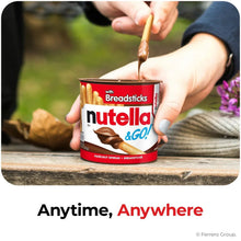 Nutella & GO! hazelnut spread cup with breadsticks, held while dipping with a stick