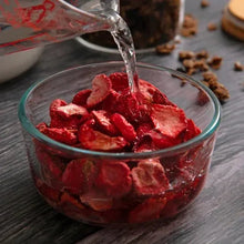 Freeze-dried strawberry slices being poured into a glass bowl