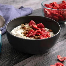 Black bowl topped with freeze-dried strawberry slices and cream