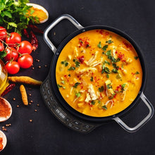 Portable black induction cooktop holding a pot of soup, with handle