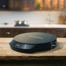 Black induction cooktop on countertop with size markings and control buttons