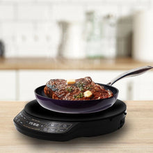 Black induction cooktop with frying pan, stovetop controls visible