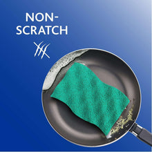 Green scrunge sponge on skillet surface with blue foam backing