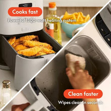 Air fryer with open basket of breaded food and removable drawer being wiped clean