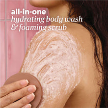 Foaming body scrub being applied to skin with beige scrubber brush