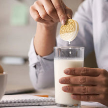 OREO cookie held above a glass of milk by a raised hand