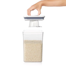 Rice measuring cup being set onto the clear rice container lid
