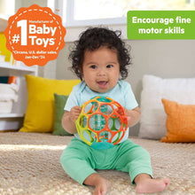 Colorful baby rattle ball with open ring design, clear sound chamber, held by baby