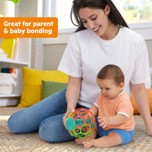 Colorful baby rattle ball with clear inserts, held during floor play