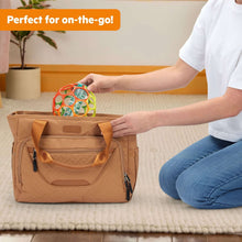 Colorful baby rattle ball with clear inserts sitting in tan tote bag