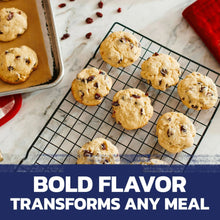 Baked cookies with dark fruit pieces cooling on a wire rack