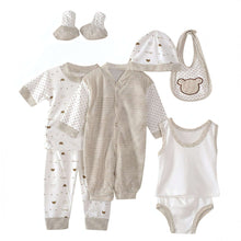 Baby layette set with striped romper, patterned pajama, bib, hat, and socks