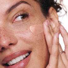 Person applying facial lotion to cheek and eye area
