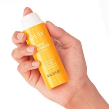 Hands holding Olay Daily Radiance Lotion bottle, lightweight orange formula