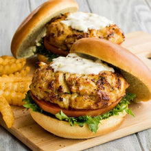 Sandwich on a wooden board with Old Bay-seasoned patty, greens, and shrimp