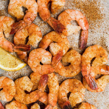 Seasoned shrimp with visible spice coating and lemon wedges on a tray