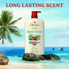 Fiji body wash bottle with red pump on rocks near a tropical shoreline.