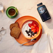 Men's multivitamin bottle with breakfast bowl of yogurt, strawberries, and blueberries