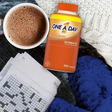 Women’s multivitamin bottle with 300 tablets beside coffee cup and blue cloth