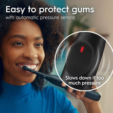 Black electric toothbrush handle with red pressure indicator light near grip