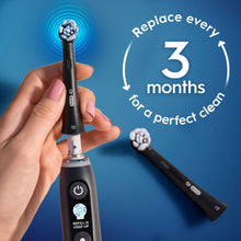 Oral-B iO brush head held in hand with replace graphic and blue bristle top