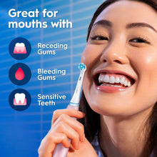 Pink rechargeable toothbrush with brush head held near teeth by person