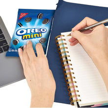 Mini sandwich cookie pack held near a notebook, with cookies shown on the wrapper