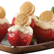 Mini sandwich cookies on top of sliced strawberries and cream in a bowl