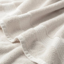 Cream organic cotton towel fabric close-up, textured loops and waffle weave