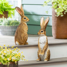 Two ornamental hare figurines, tan and white, standing poses with long ears