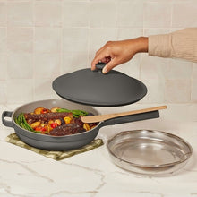 Dark gray skillet with steamer mesh insert and matching lid, wooden handle shown