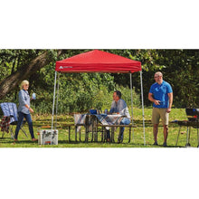 Red outdoor canopy tent shelter with white frame set up in a backyard