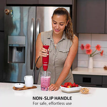 Red immersion hand blender held with measuring beaker on the counter