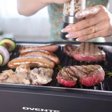Smokeless griddle grill system with steak, chicken, and seasoning on the grilling grate