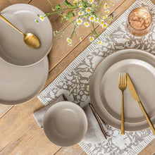 Taupe stoneware dinnerware set with plates and bowls, gold utensils, and napkins