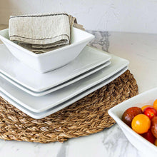 Stack of white square plates and bowls with folded cloth napkins