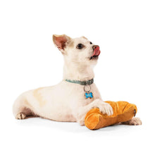 Orange croissant-shaped plush dog toy on white floor