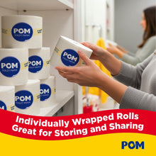 Toilet paper roll held in hand, with additional wrapped rolls stacked on a shelf