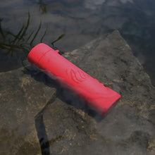 Red rechargeable hand warmer on stone surface with heat icon