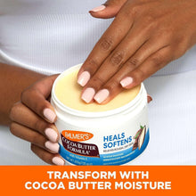 Hands holding a cocoa butter moisturizer jar with vitamin E, white lid and label