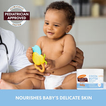 Cocoa butter baby balm jar beside smiling baby holding a pacifier
