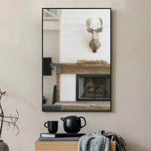 Rectangular wall mirror with black frame and reflected room view