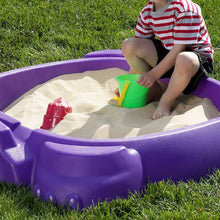 Play sand in a purple sandbox with a child playing and using a green scoop