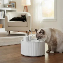 Pet water fountain with faucet and white ribbed base; light-colored cat drinking