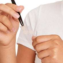 Person applying an acne dot with tweezers