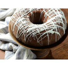 Chocolate ring pastry with white drizzle on a wooden bowl
