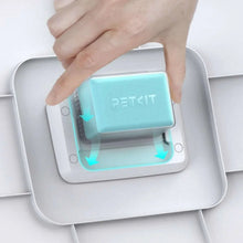 Hand placing turquoise PETKIT scent cartridge into white pet waste bin