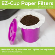 Paper coffee filter holding dark grounds in purple reusable cup with white scoop